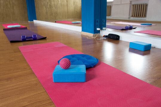 Colorful fitness studio with pink yoga mats, blue exercise blocks, dumbbells and massage ball, modern wellness workout space, stretching, pilates, exercise, relaxation and healthy lifestyle indoors
