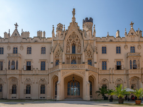 A view of Lednice Castle in the Czech Republic. A neo-Gothic castle in Moravia surrounded by a park. A historic park and garden in summer. Flowering plants in the park.