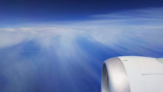 Airplane jet engine cruising high above a brilliant turquoise ocean and vibrant blue sky on the way to Punta Cana, Dominican Republic