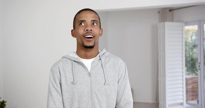High speed photography for dynamic scenes, man in grey hoodie standing indoors, looking surprised an