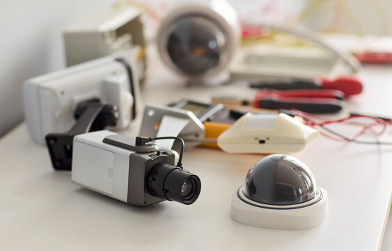 Security cameras and surveillance equipment for installation. Dome units, wiring and tools arranged on a workbench indoors for security system setup. Reliable protection technology concept.