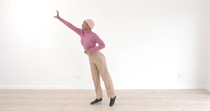 Woman in pink sweater striking superhero pose in minimalist room, feeling empowered