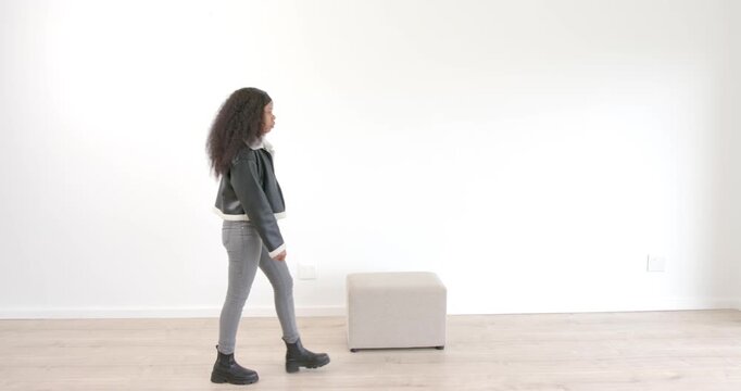 Sitting on stool in minimalist room, woman contemplating quietly