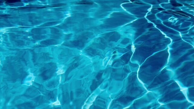 Horizontal texture shot of blue water ripples and bright sun reflections on mosaic tiles inside swimming pool at luxury resort. Clear turquoise aquatic background for summer vacation and wellness.