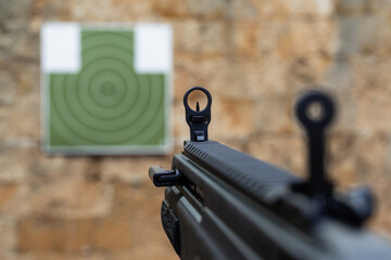 First person shooter view aiming short nine millimeter carbine mechanical iron aperture sights at green silhouette torso target during tactical shooting range training © Dmitri