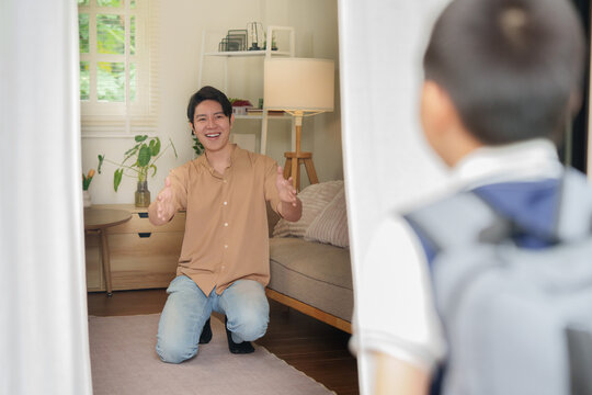 Asian father welcoming son with open arms at home for back to school routine