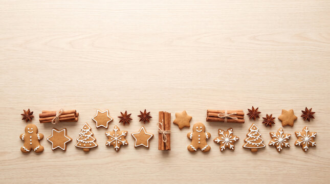 Row of Christmas gingerbread cookies with cinnamon and star anise on light wood