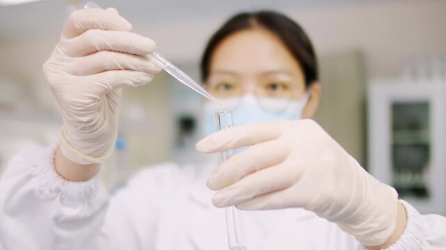 Female scientist in white lab coat protective gloves adding pipette dropping a colored liquid to petri dish to conduct scientific experiments lab research chemistry studies, innovative laboratory