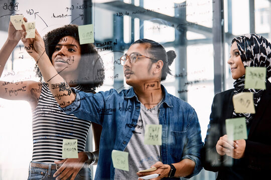 Meeting, planning and business people with sticky note on glass board for schedule or project tasks. Group, employees or colleagues with ideas for creative strategy, company reminder or work agenda