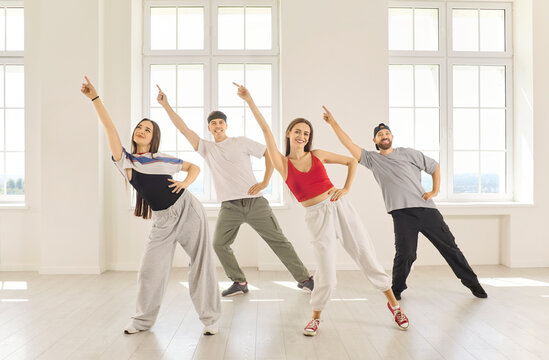 Dancers perform coordinated group dance in studio. Four adults strike coordinated poses in a room, expressing friendship, rhythm and confidence. A vibrant concept of shared creative energy.