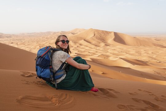Female hiker on a red sand dune in the desert, dune landscape Erg Chebbi, Merzouga, Sahara, Morocco