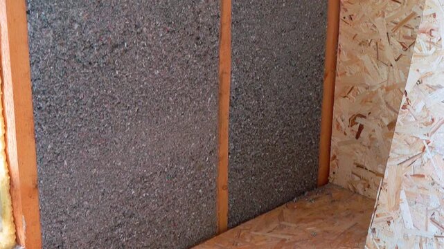 Timber frame wall insulated with wet spray cellulose ecowool next to osb board sheet. Energy efficient building construction and thermal insulation.
