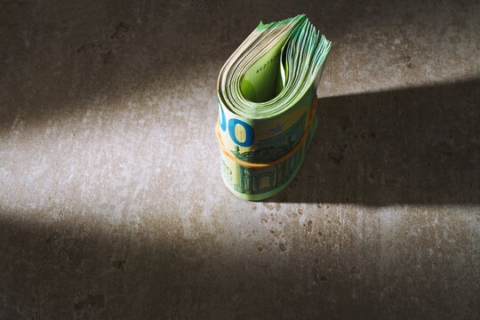 A stack of euro banknotes. isolated against a plain background in dramatic light. A thick roll of euro banknotes.