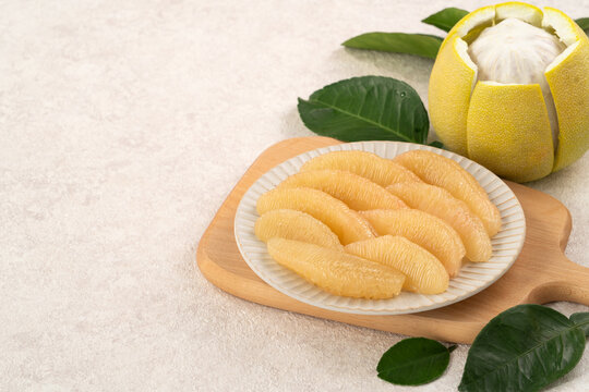 Fresh pomelo fruit with leaf on white table background.