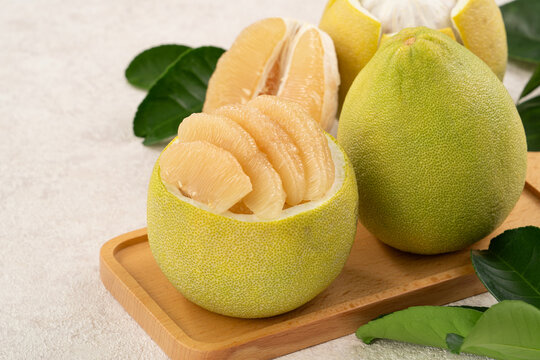 Fresh pomelo fruit with leaf on white table background.