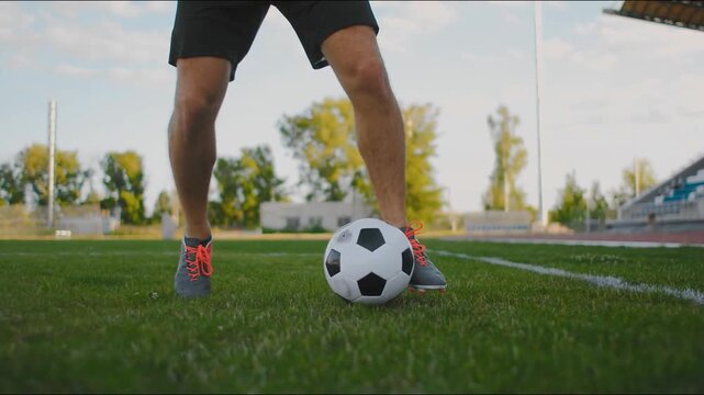 Professional footballer soccer ball on stadium. Young male man leg foot kicking ball at green field. Sportsman practicing tricks at meadow background. Freestyle football. dribble court. training sport