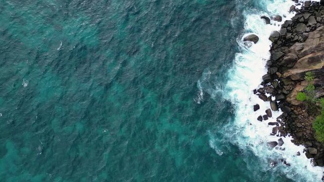 Weh Island, Indonesia : Top down aerial drone footage of wave breaks onto rocky cliff surrounded by tropical forest near Gua Sarang, famous tourist spot in Weh Island of Sabang, Aceh, Indonesia