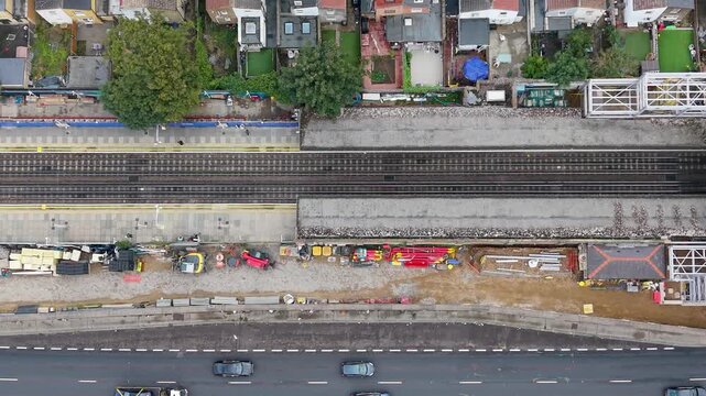 Leyton tube station renovation seen from above, aerial right pan shows new lift shafts and footbridge steelwork over rail tracks, fenced storage areas and building materials.