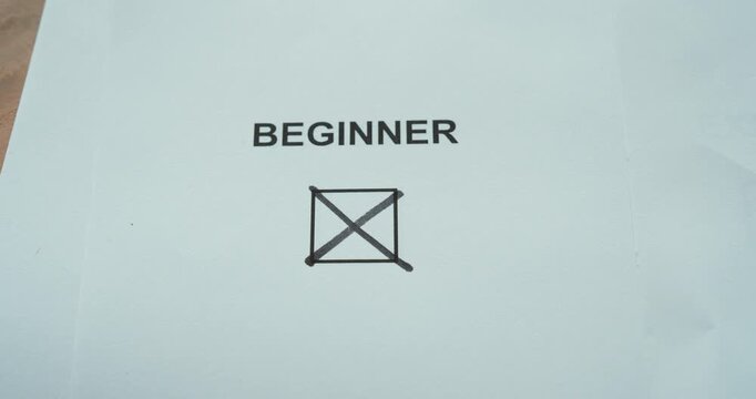 Close-up of a person marking a beginner checkbox on a skill level selection card.