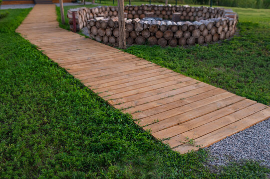 Wooden slat path across the lawn; wood treatment and environmental protection. Wood oil and impregnating agents. Eco-friendly finish.