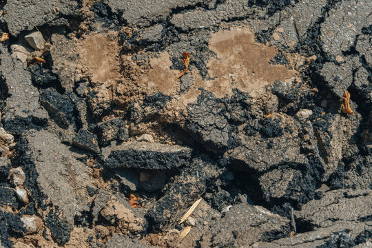 Close up background of severely cracked, broken, and destroyed asphalt pavement surface during road repair.