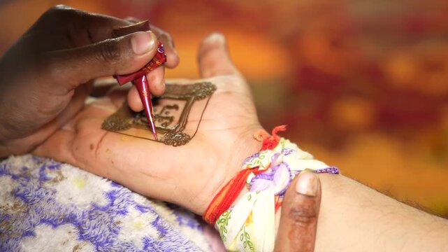 Indian woman applying henna mehendi design on hand during a wedding in Delhi