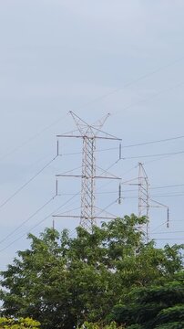 : High voltage electricity transmission towers standing on a mountain ridge, surrounded by a natural landscape under daylight.