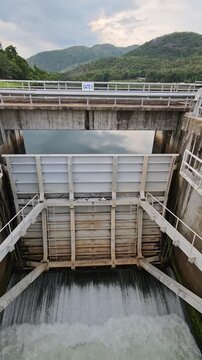 A large water release gate at a dam controlling the flow of water through a reservoir and downstream channel.