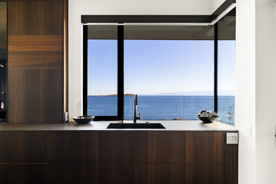 Dark kitchen sink with ocean view through black window