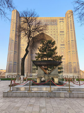 Bibi-Khanym Mosque entrance portal with ornate tilework and marble Quran stand in Samarkand. Monumental Islamic facade bathed in golden light, ideal for travel and heritage publications.