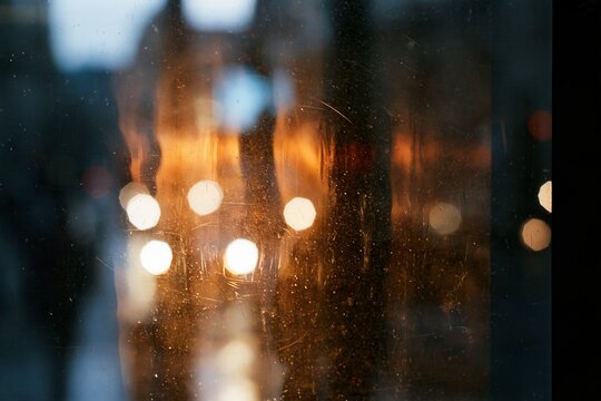 Cinematic light leak overlay with blurred city bokeh, film grain, dust and scratches on dark distressed retro background