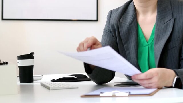 Close up of a caucasian woman filling out visa application documents, office desk with a computer 