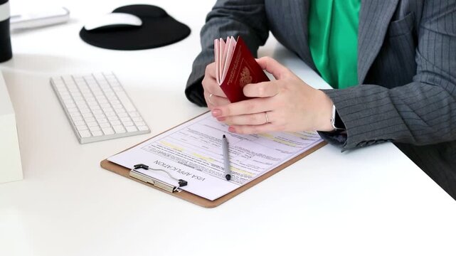 Close up of a caucasian woman checking a Russian passport and filling out visa application document 