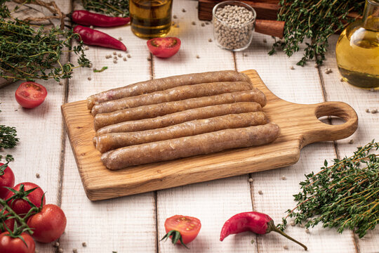 Raw chicken sausages arranged neatly on wooden cutting board ready for cooking
