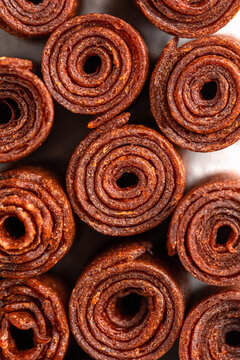 Appetizing sweet fruit leather rolls arranged in neat columns showing spiral texture on grey surface closeup