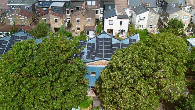 Aerial view of a residential building with solar panels on the roof, surrounded by lush green trees and neighboring houses in London, England, United Kingdom.