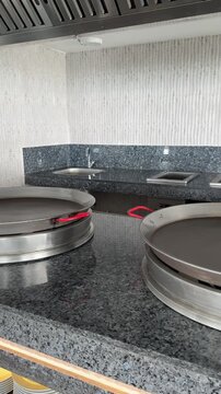 Large electric frying pan on restaurant kitchen, commercial cooking surface, chefs preparing bulk meals efficiently.