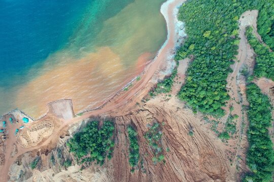 Aerial view of PT Ceria Nugraha Indotama industrial site showing sediment runoff into the sea, dirt roads, and lush forest in Wolo, South East Sulawesi, Indonesia.