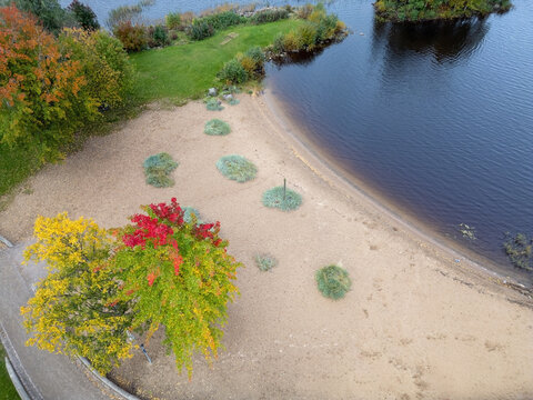 Aerial view of the Kiikeli park area featuring a sandy beach, vibrant autumn foliage with yellow and red trees, and calm water along the shoreline in Oulu, North Ostrobothnia, Finland.