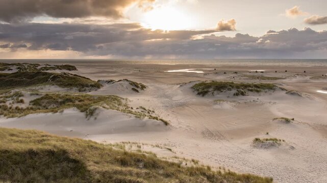 Time lapse Amrum island, Germany: sun rays emerging through the dark storm clouds at the beach of Amrum. Sunset is obscured by a thick cloud front announcing bad weather	