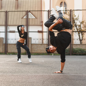 The young dancer standing on his hand. Dancing hip hop with a beautiful girl.