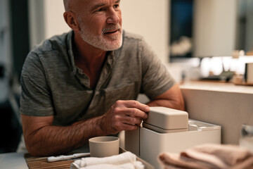 Fototapeta premium A thoughtful older man interacts with modern bathroom decor, showcasing the beauty of everyday moments, focusing on personal care and connection in a serene setting.