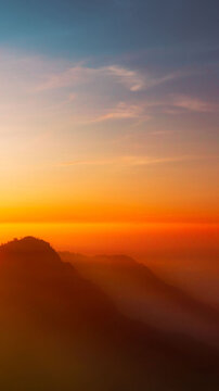 Aerial view of Mount Bromo at sunrise with golden light illuminating the misty mountain landscape in Tosari, East Java, Indonesia.