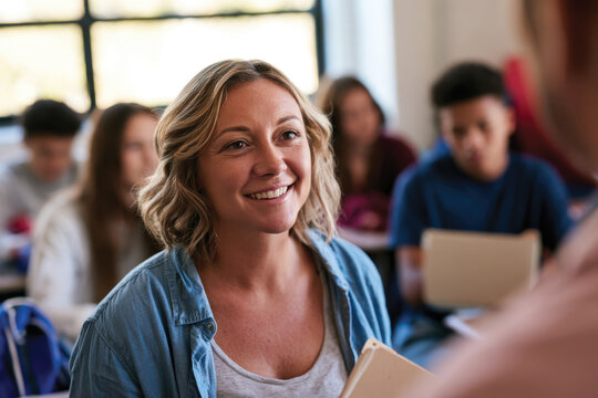 A joyful teacher smiles while interacting with students in a classroom setting, capturing the essence of education, enthusiasm, and positive learning experiences.