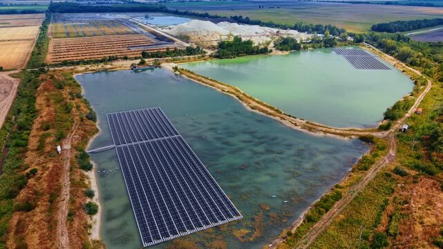 Twin artificial lakes with floating solar arrays.. Two water reservoirs host distinct photovoltaic installations adjacent to an industrial sand extraction site and farmland.