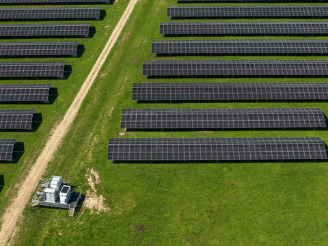 Aerial view of a large solar farm with rows of photovoltaic panels arranged on a green field in The Basin, Victoria, Australia.