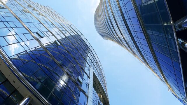 Low angle view of futuristic skyscrapers with blue glass facades reflecting the sky. Contemporary architecture in a modern financial district