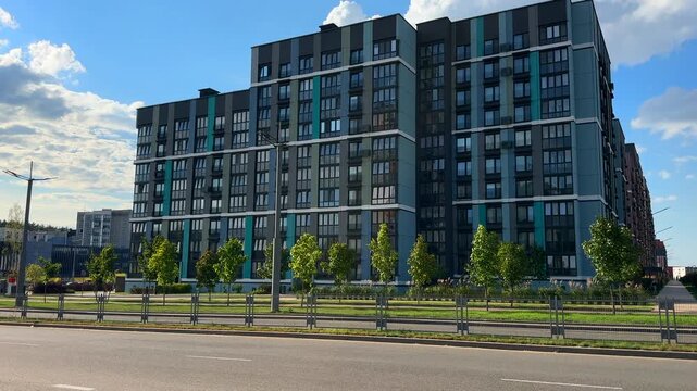 Modern apartment building with blue, gray facade. Car mooving on road city. Urban scene with contemporary architecture condo exterior. Multifamily apartment. Belarus, Minsk, September 16, 2026.