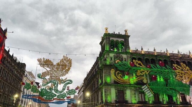 Mexico City Zocalo plaza street glows green, eagle coat arms light installation hangs above independence day crowd