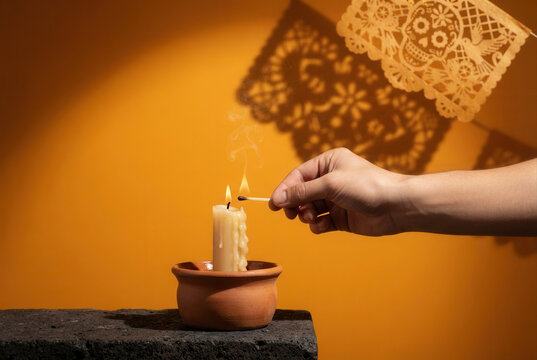 Hand light candle beside lace shadow on warm wall